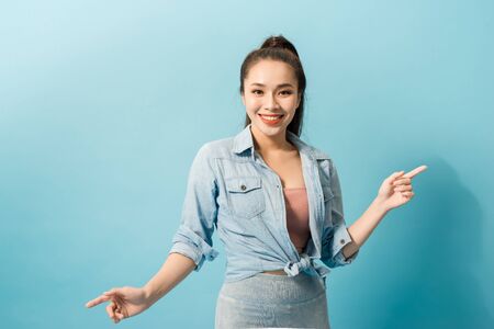 Charming excited crazy woman jumping up on light blue backgroundの写真素材
