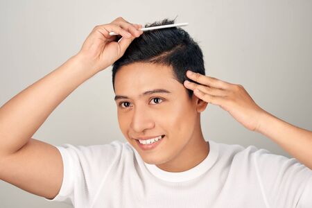 Handsome smiling Asian young man doing modern hairstyleの写真素材