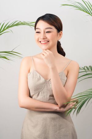 Portrait of Asian happy woman standing with green leaves around her on white backgroundの写真素材