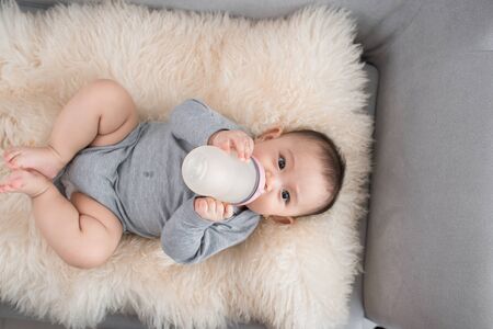 Asian baby infant eating milk from bottle, 9 months after birthの写真素材
