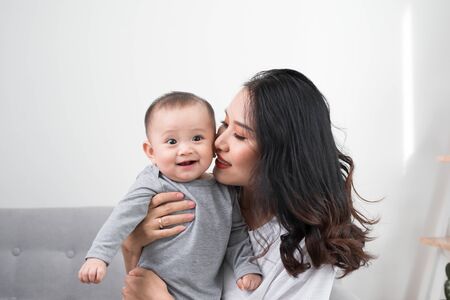 happy family at home. Mother holding baby daughter in living room in cozy weekend morningの写真素材