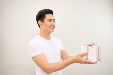 A happy handsome man presenting some gifts. Isolated on white background.の写真素材