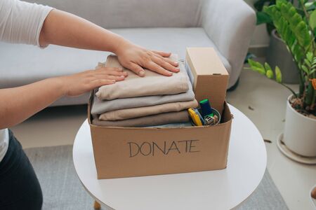 Close-up Of A Woman Putting Clothes Inside Donation Boxの写真素材