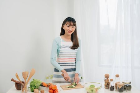Young woman cutting vegetables in the kitchen. Woman cooking healthy food.の写真素材