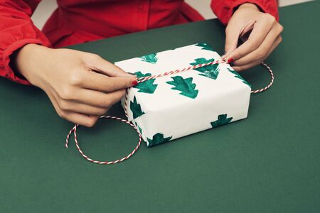 Closeup of woman's hands wrapping Christmas giftの写真素材