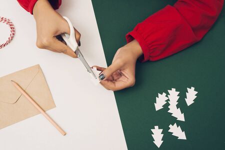 Woman cutting Christmas tree paper with envelopement and color paper. Noel diyの写真素材
