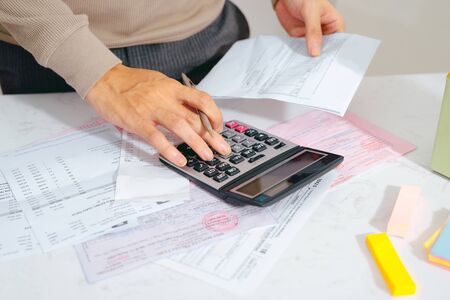 Hand man doing finances and calculate on desk about cost at home office.の写真素材
