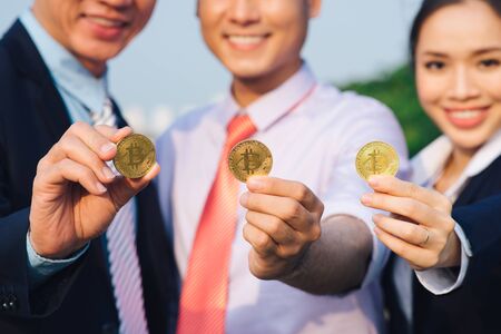 Young Asian Businessman holding golden bitcoin in front of his international Multi ethnic team in modern city.の写真素材