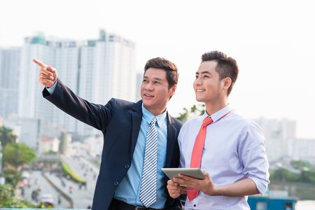 Young handsome businessmen discussing project on digital tablet computer outdoorsの写真素材