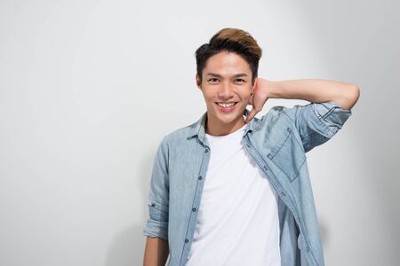 Portrait of Asian stunning, smiling, cool man in jeans shirt looking at camera, isolated on white backgroundの写真素材