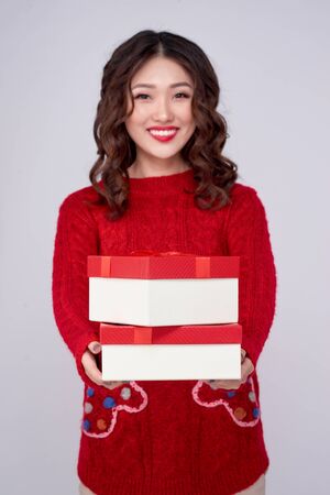 Asian woman in red warm clothes with gifts. Holidays New Year and Christmas.の写真素材