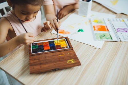 Young Asian beautiful mom with her daughter kid painting at home.の写真素材