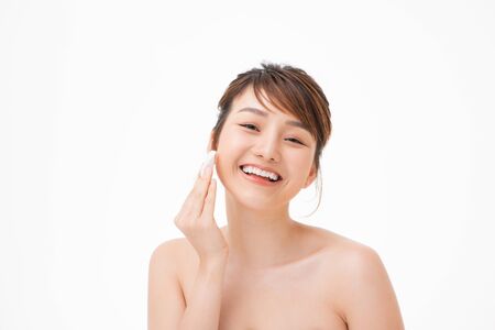 Beauty portrait of a happy half naked asian woman removing make-up with a cotton padの写真素材