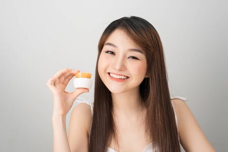 Smiling young asian woman showing skincare product. Beauty concept.の写真素材
