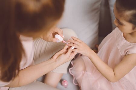 Beautiful young asian mother is painting the nail varnish to her cute little daughter.の写真素材