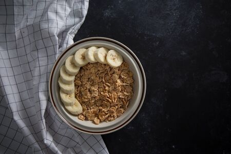 Organic healthy oatmeal porridge with fresh bananas. The white porcelain bowl with napkinの写真素材