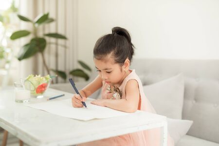 Little girl drawing picture at table with painting tools indoors