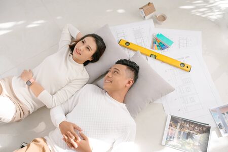 Portrait of happy cheerful couple looking at construction house planの写真素材