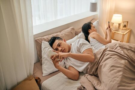 Young couple with smartphones in their bedの写真素材