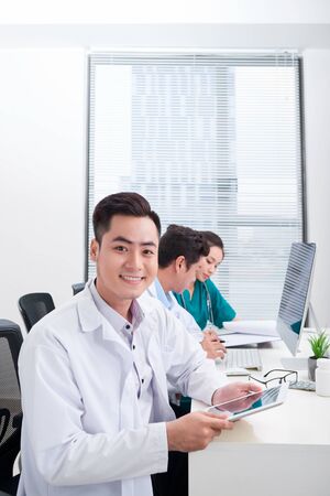 Happy doctor man with medical staff at the hospital sitting at officeの写真素材