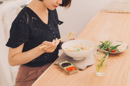 Vietnamese Pho Noodle Soup. Beef with Chilli, Basil, Rice Noodles, Bean Shoots showing noodles picked up with Chopsticksの写真素材