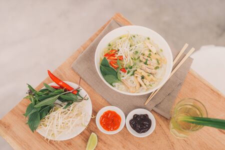 Pho Bo - Vietnamese fresh rice noodle soup with beef, herbs and chili. Stock being poured. Vietnam's...