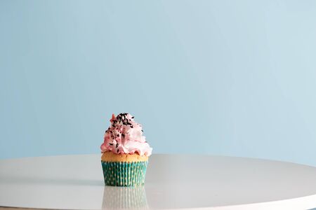 Cupcake with pink cream icing on table