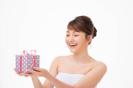 Happy young woman holding small gift box isolated on a white backgroundの写真素材