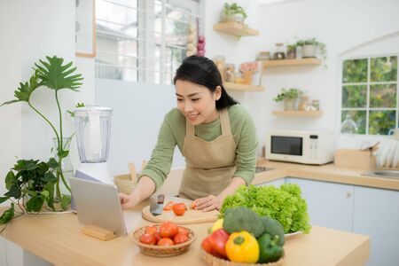 Woman In Kitchen Following Recipe On Digital Tabletの写真素材