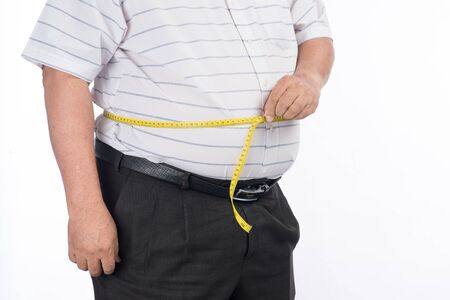 Fat mature man measuring his belly with measurement tape, isolated on white backgroundの写真素材