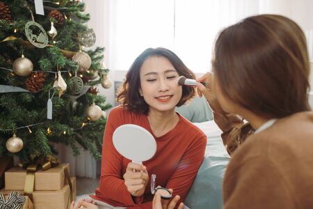 Make up, friendship and leisure concept. Two smiling girls applying make up at home.の写真素材