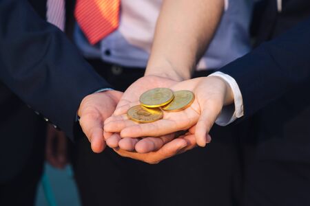 Young Asian Businessman holding golden bitcoin in front of his international Multi ethnic team in...