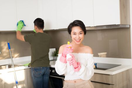 Young happy Asian couple is having fun while doing cleaning at home.の写真素材