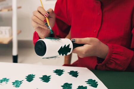 Woman painting on her Chirstmas tree paper. Xmas concept