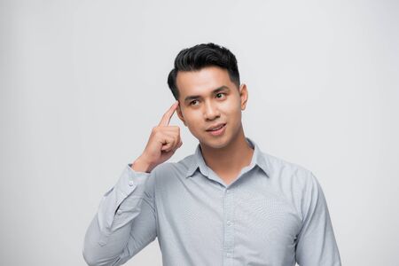 Businessman pointing at his head, having an idea, isolated on white studio backgroundの写真素材