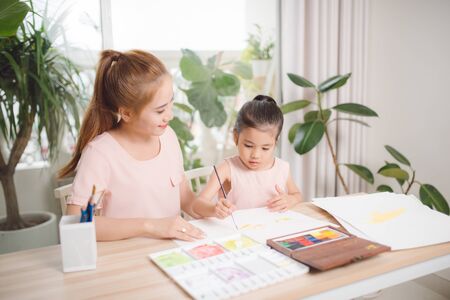 Little girl painting with her mother laying in livingroomの写真素材
