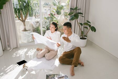 repair, building, renovation and people concept - close up of happy couple looking at blueprint at homeの写真素材