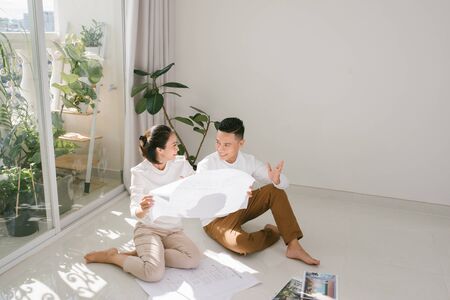 repair, building, renovation and people concept - close up of happy couple looking at blueprint at...