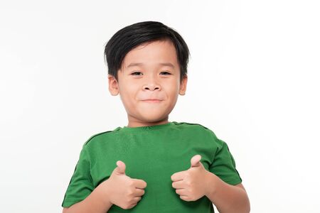 childhood, gesture and people concept - portrait of smiling boy showing thumbs up over light...