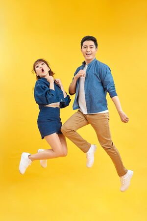 Full length body size photo funky she her he him his pair jumping high raised fists yell scream shout loud wear casual jeans denim white t-shirts isolated yellow backgroundの写真素材
