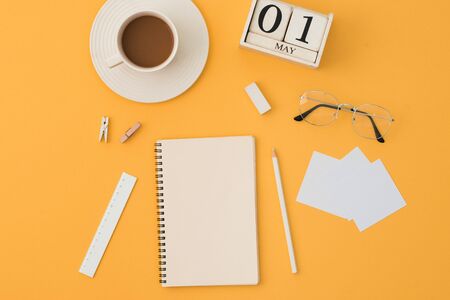Top view of work place with coffee cup, notebook, ruler, eraser, pencil, glasses on orange background. working place concept.の写真素材
