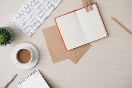 Modern minimalistic work place. Keyboard, notebook, envelope, glasses, pen, pencil, coffee on wood table. Top view with copy space, flat lay