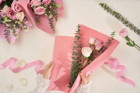 Making pink flowers bouquets with scissor on white background. Holiday, mothers day, valentine day concept. Top view, flatlayの写真素材