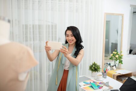 Beautiful Asian fashion designer taking a picture of new productの写真素材
