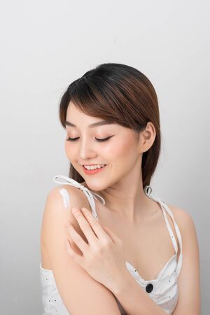 Asian woman applying sunscreen/sun block lotion on her body for protect her skin from UV sunlight.の写真素材