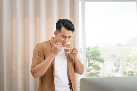 Asian freelancer man is working on his laptop in his apartment. Concept of freelance creative works.の写真素材