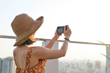 Asian Woman taking a photo using professional camera. Young photographer, natural light.の写真素材