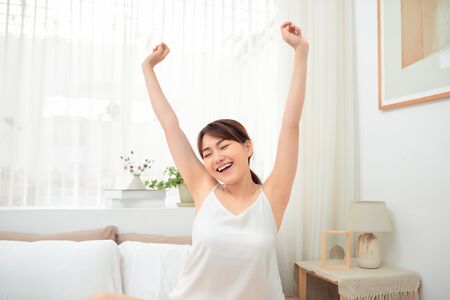 Asian woman stretching in bed after wake upの写真素材