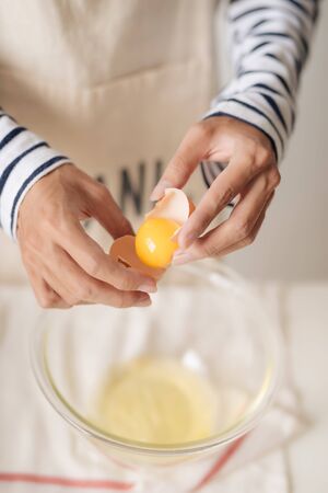 broken egg in hands with separated yolk closeup の写真素材