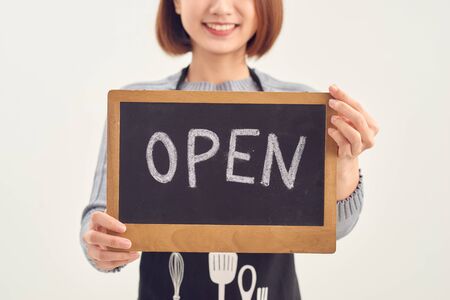 It's open here. A smiling woman is holding a sign with the inscription "open" on a white background isolated.の写真素材